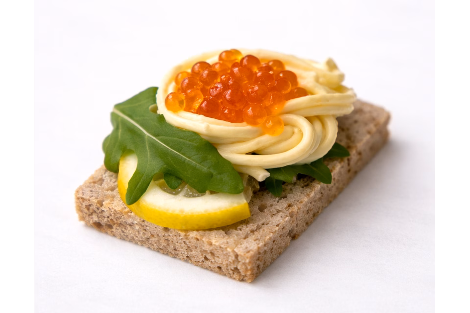 სადღესასწაულო კანაპე შავ პურზე, წითელი ხიზილალით, ლიმონის ნაჭრითა და კარაქით