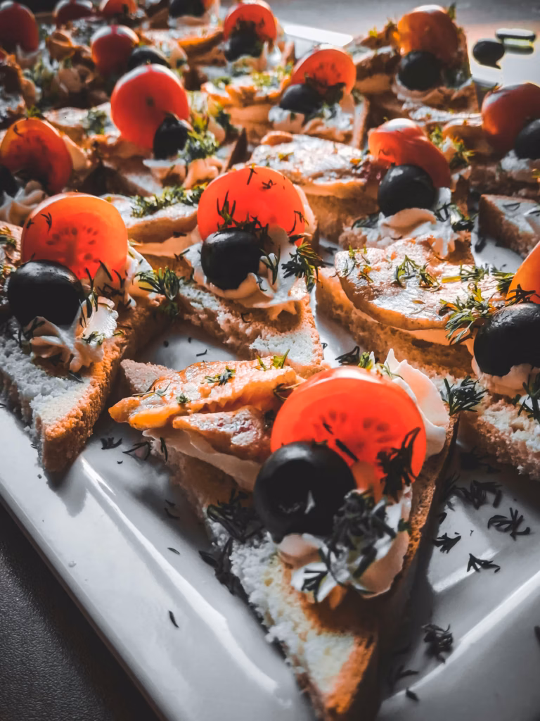 წითელი ორაგულის კანაპეები ლიმონის ნაჭრებითა და მწვანილით, სერვირებული ქეითერინგისთვის.